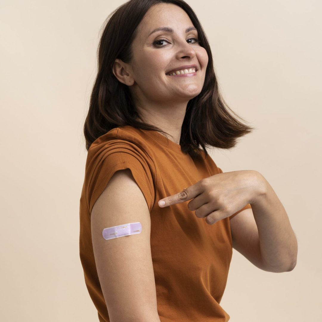 smiley-woman-showing-sticker-arm-after-getting-vaccine smiley-woman-showing-sticker-arm-after-getting-vaccine